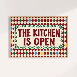 Open kitchen harlequin print reading THE KITCHEN IS OPEN on a burgundy harlequin pattern