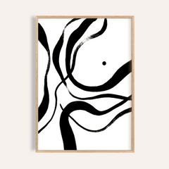 Framed black and white art with abstract black brush strokes on a white background in a light wood frame