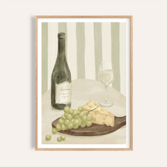 Framed print close-up of grapes, cheese and a bottle with glass in soft green tones