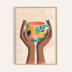 Framed print of hands holding a colourful floral mug in teal, yellow and pink on beige