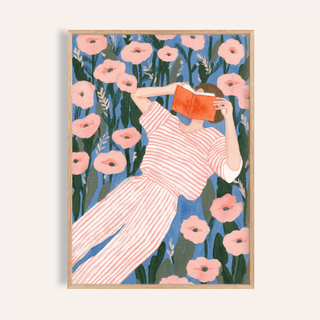 Framed Woman Reading Art Print showing a person in pink striped clothes reading an orange book surrounded by pink flowers