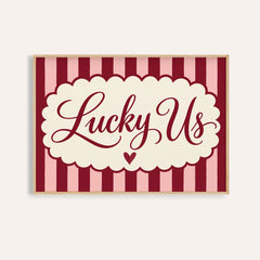Above bed wall art with Lucky Us in burgundy script on pink and burgundy stripes