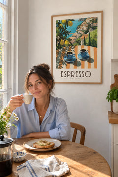 Woman drinking coffee at her kitchen table under the Amalfi Espresso print