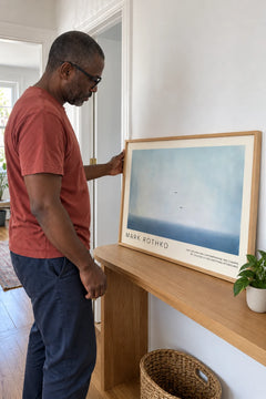 Man placing the Sky Horizon print on a console table in his hallway