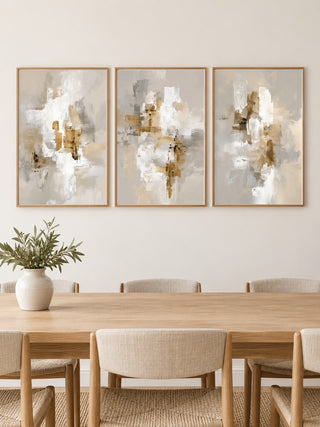 Neutral dining room wall art hung at eye level above a dining table: Neutral Brushstrokes, Modern Gold Abstract and Neutral Abstract Print shown framed side by side (frames not included)