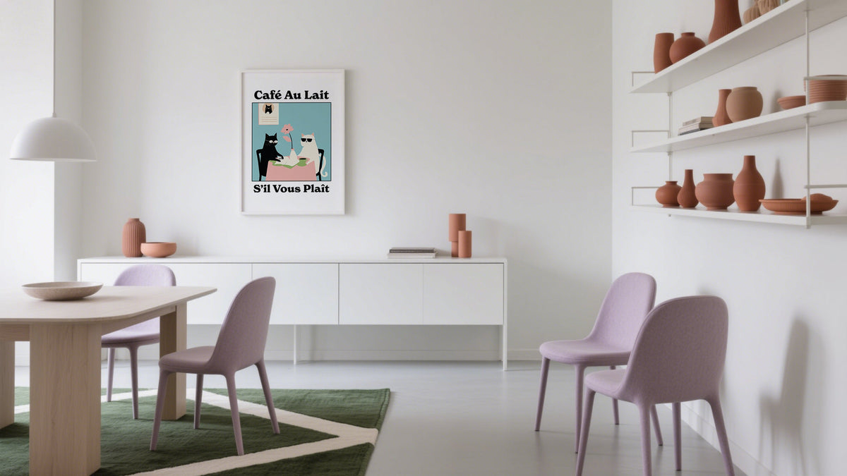 Framed Café Au Lait cat illustration poster styled beside a bed in a cozy room with stacked journals, showcasing playful prints and posters in home decor.