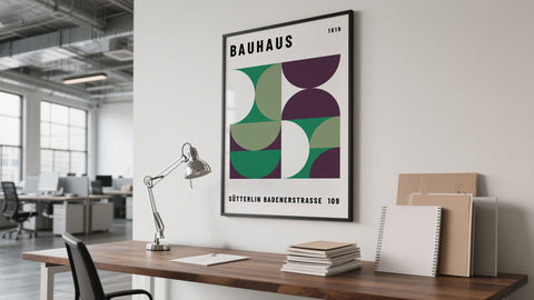 Framed extra large abstract wall art with bold geometric shapes in red, yellow, blue, and black leaning against a neutral wall in a modern office