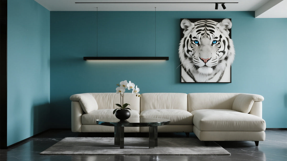 A light-colored sectional sofa faces a round black coffee table with a potted white orchid. A large painting of a white tiger with blue eyes hangs on a teal wall. A linear light fixture is mounted above the sofa. The floor is dark and glossy.