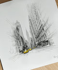Black and white cityscape drawing with yellow taxis on a wooden surface