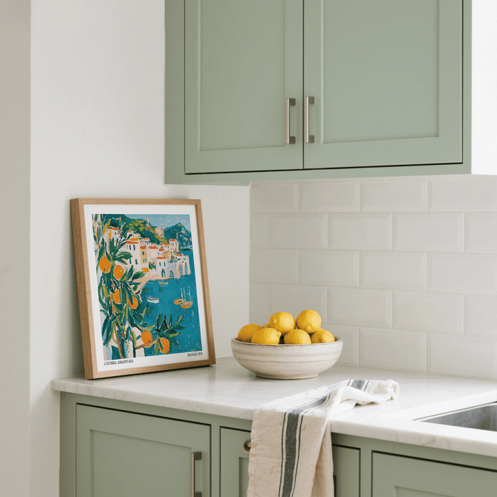 Amalfi Coast print leaning on kitchen countertop with pastel cabinets and bowl of lemons