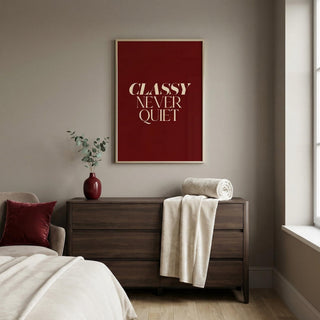 Modern bedroom with a dresser, bed, and framed classy tyography poster on the wall.