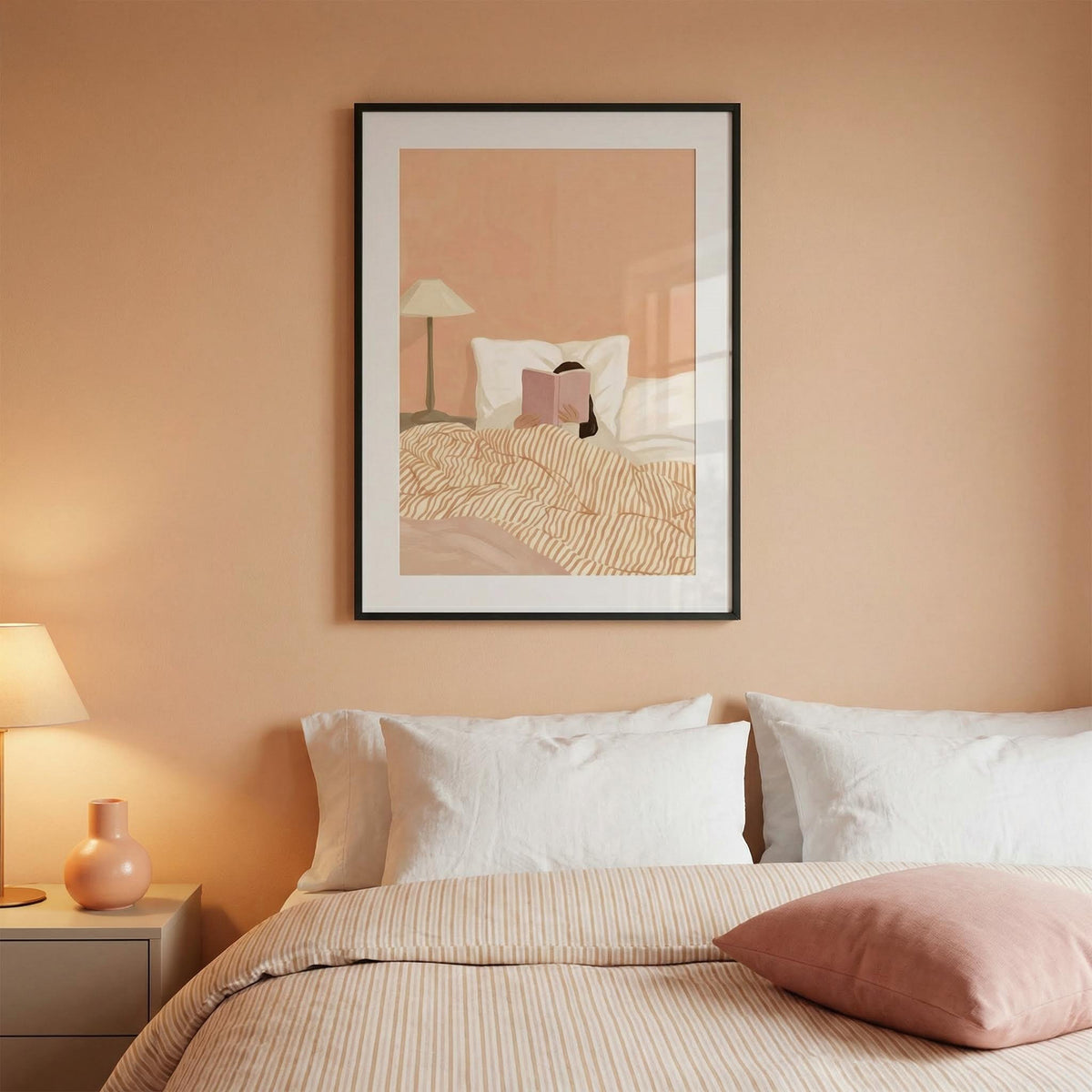 Framed artwork above a bed with pink walls and decor