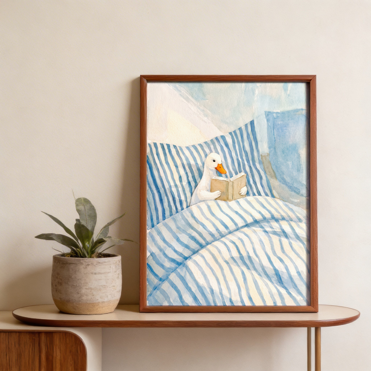 Soft watercolor poster of a duck reading an open book while tucked into striped blankets