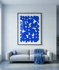 Modern living room with a gray sofa, blue abstract art, and a plant.