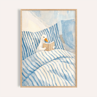 Framed Duck Reading Art Print showing a duck reading a book in blue and white striped bedding