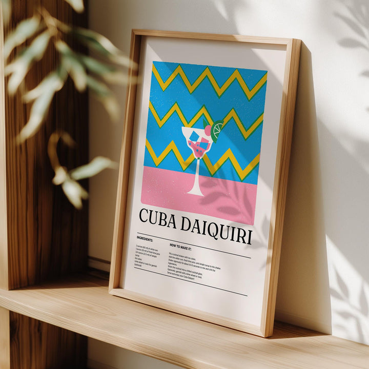 Framed Alcohol Artwork with blue and yellow zigzag background and pink daiquiri print leaning on a wooden shelf
