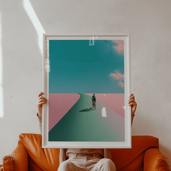 Minimal wall art print depicting a single cyclist riding toward the horizon with wide sky and clouds
