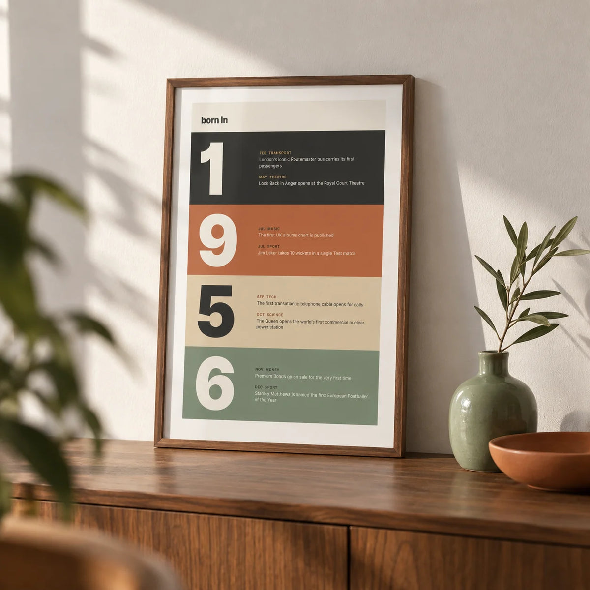 1956 Typography Print, a small A4 framed print leaning on a walnut sideboard in a living room