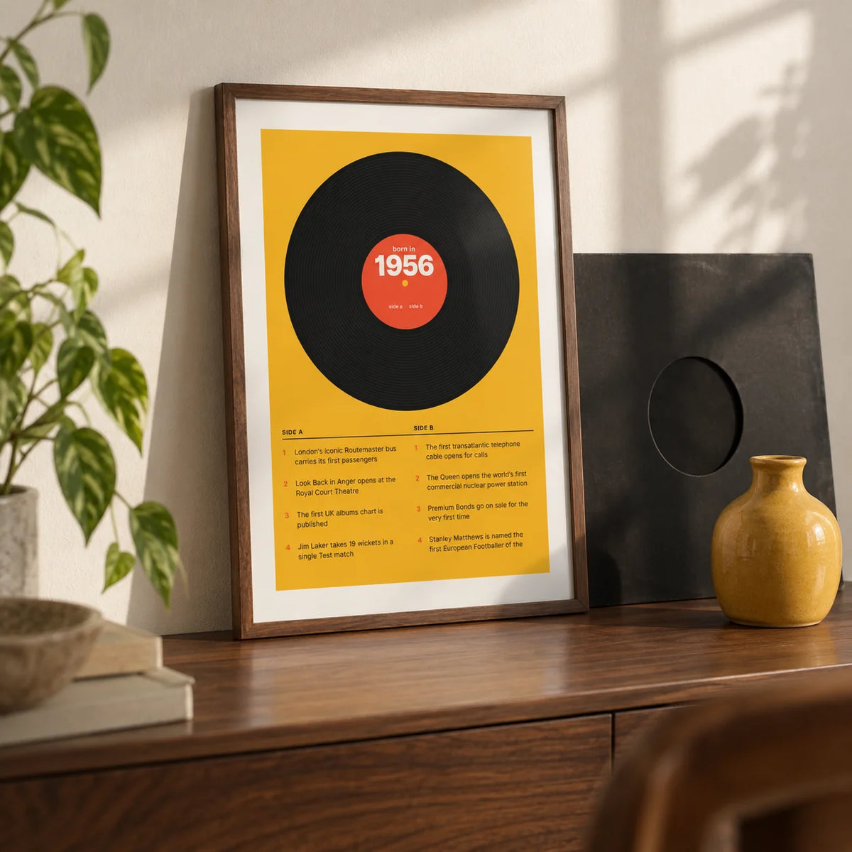 1956 Vinyl Record Print, a small A4 framed print leaning on a walnut shelf in a living room