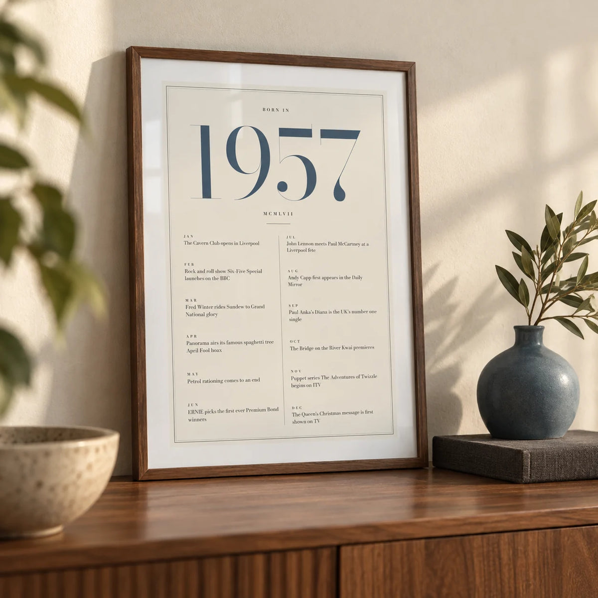 1957 Blue Birthday Print, a small A4 framed print leaning on a walnut sideboard in a living room