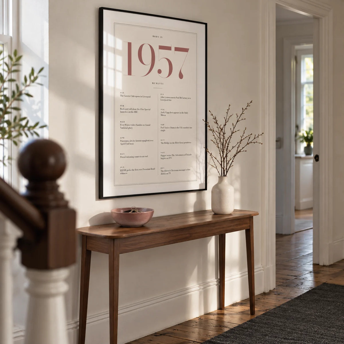 1957 Pink Birthday Print, framed on the wall of a bright hallway in a renovated British terrace with warm white walls and original timber floorboards