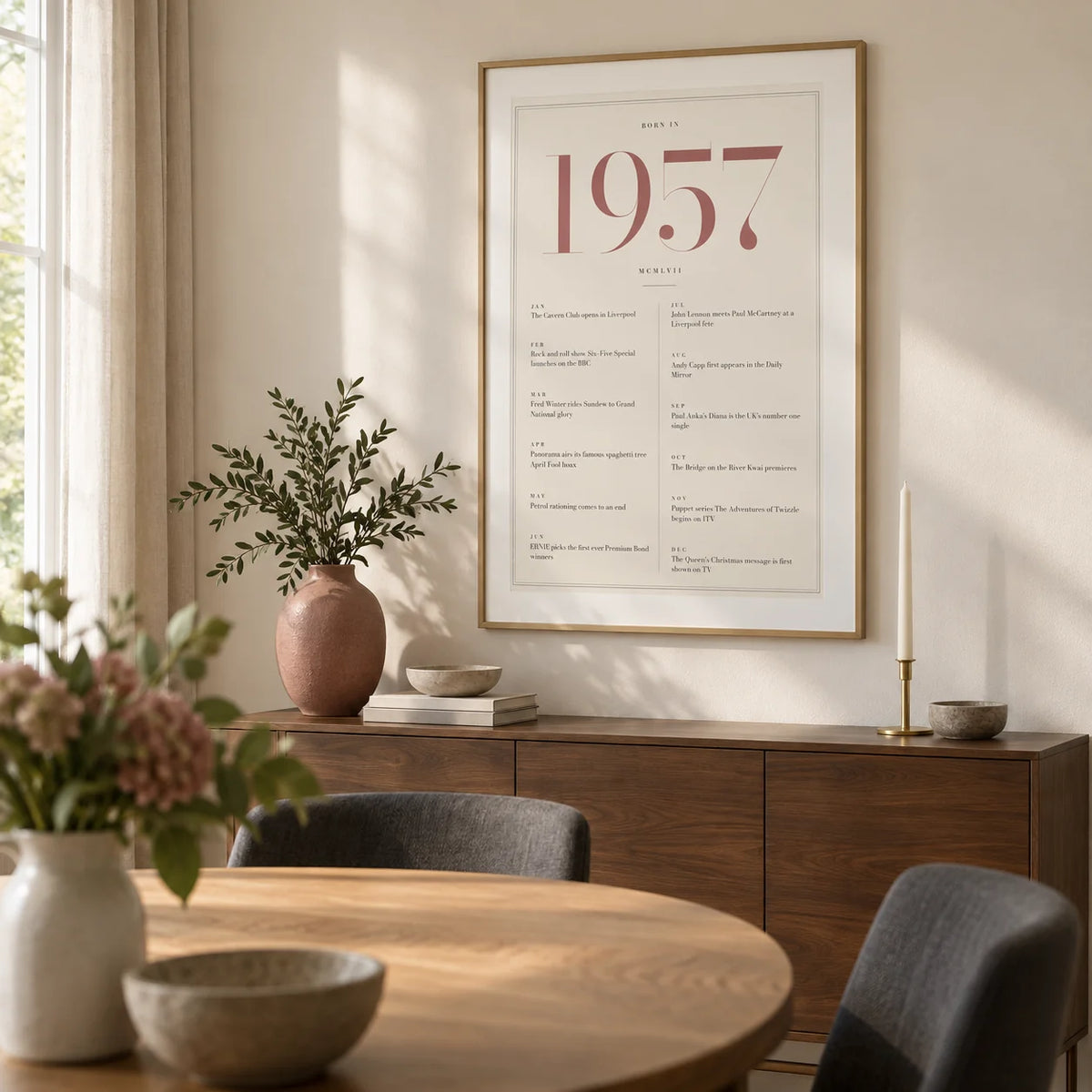 1957 Pink Birthday Print, framed on the wall of a contemporary dining room in a British family home with a pale ivory wall and a round oak dining table