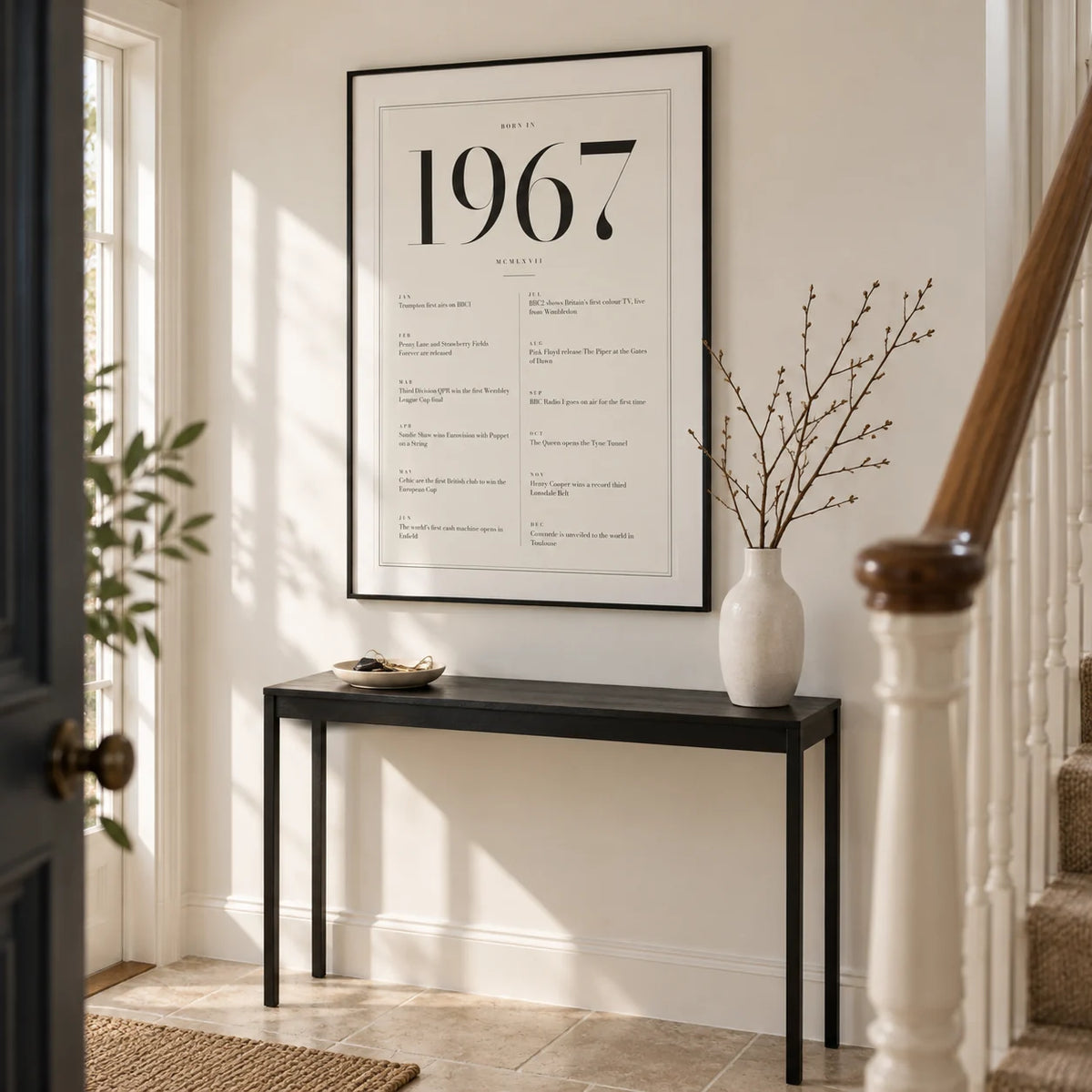 1967 Birthday Print, framed on the wall of a bright entrance hall in a renovated British semi with warm white walls and a plain limestone floor