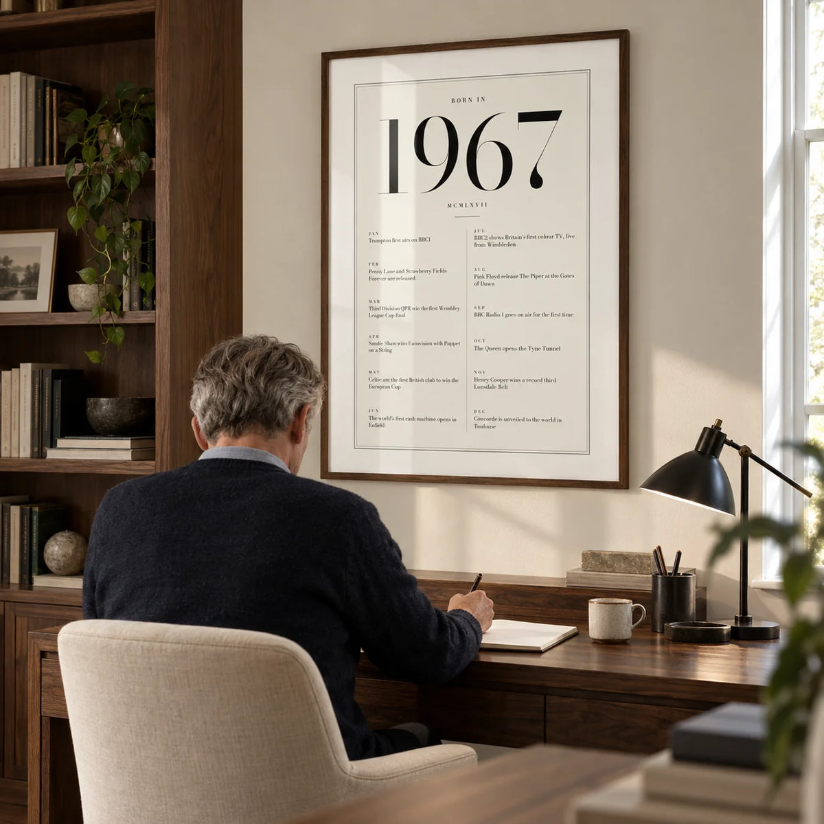 1967 Birthday Print, framed on the wall of a quiet home study for an adult around 60 with an ivory wall and a built-in walnut bookcase to one side