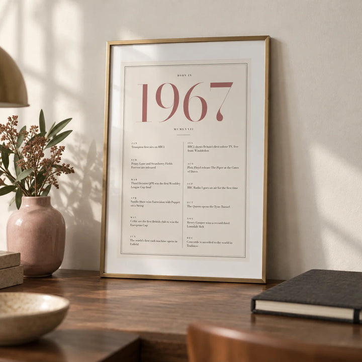 1967 Pink Birthday Print, a small A4 framed print leaning on a walnut desk