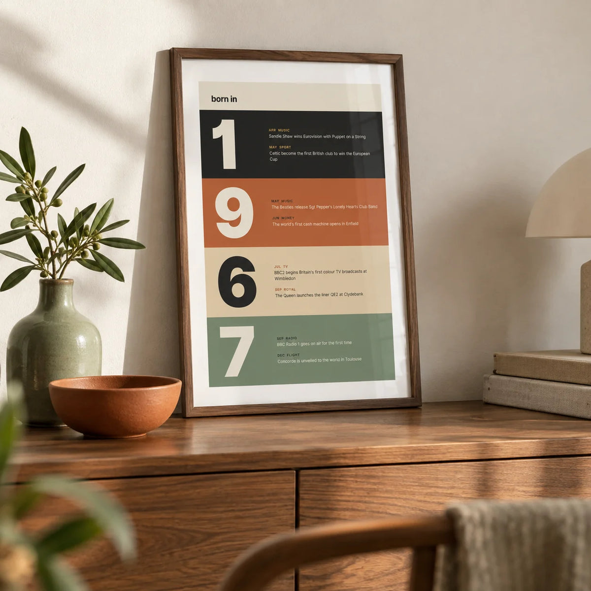 1967 Typography Print, a small A4 framed print leaning on a walnut sideboard in a living room