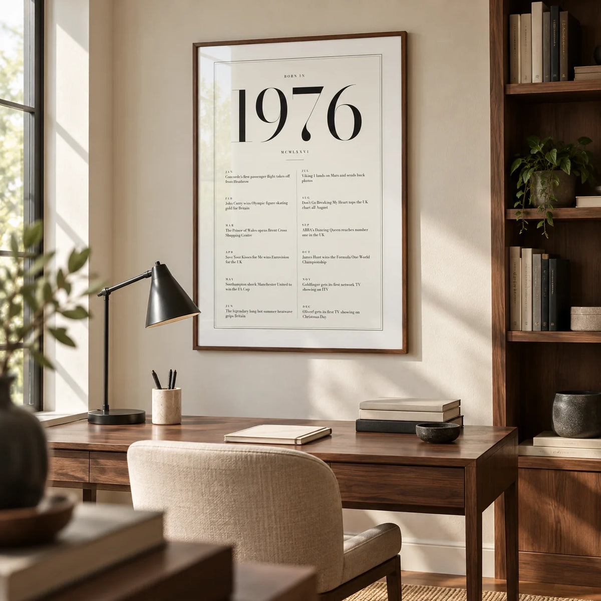 1976 Birthday Print, framed on the wall of a quiet home study for a design-conscious adult around 50 with an ivory wall and fitted walnut shelving