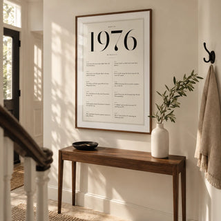1976 Birthday Print, framed on the wall of a welcoming hallway in a renovated UK terrace with an ivory wall and pale limestone floor