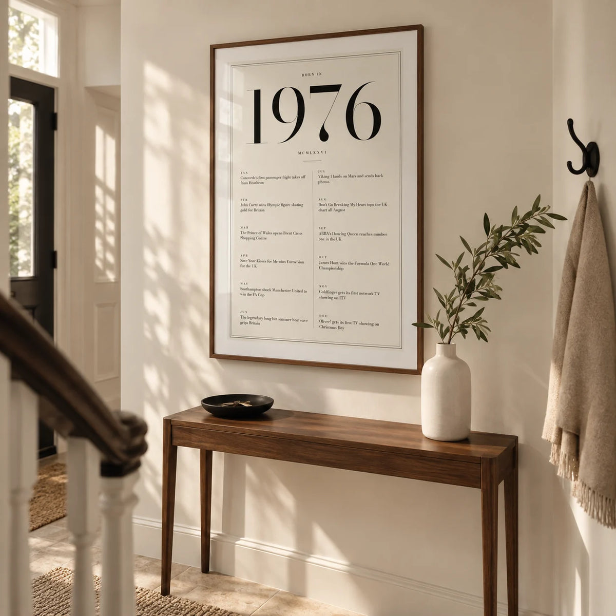 1976 Birthday Print, framed on the wall of a welcoming hallway in a renovated UK terrace with an ivory wall and pale limestone floor