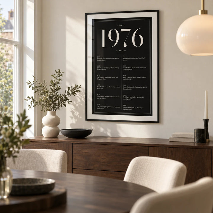 1976 Black Birthday Print, framed on the wall of a modern dining room in a British semi-detached home with an ivory wall and a dark oak dining table