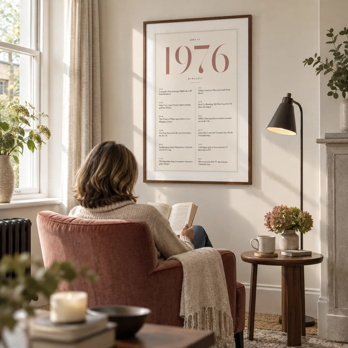 1976 Pink Birthday Print, framed on the wall of a quiet reading corner beside a tall window in a UK sitting room with an ivory wall in a living room