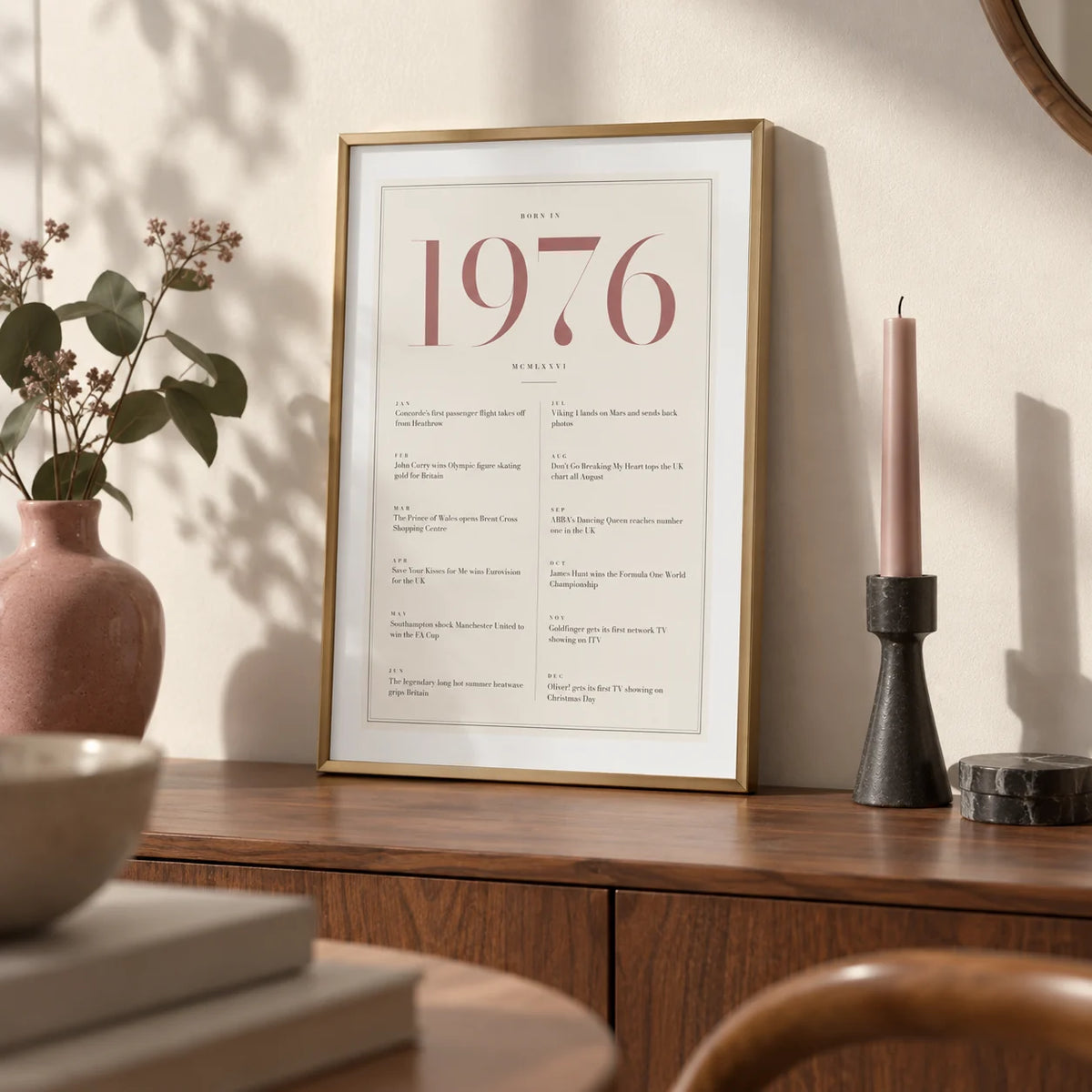 1976 Pink Birthday Print, a small A4 framed print leaning on a walnut sideboard in a living room