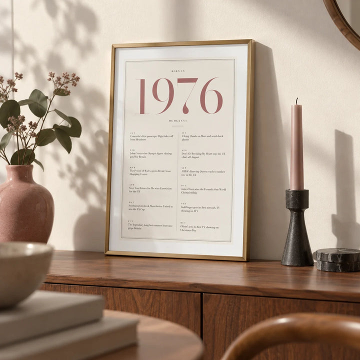 1976 Pink Birthday Print, a small A4 framed print leaning on a walnut sideboard in a living room
