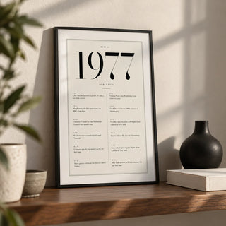 1977 Birthday Print, a small A4 framed print leaning on a walnut shelf in a living room