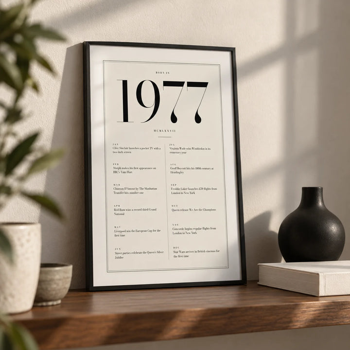 1977 Birthday Print, a small A4 framed print leaning on a walnut shelf in a living room