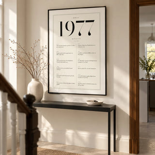 1977 Birthday Print, framed on the wall of a smart hallway in a renovated British terrace with warm white walls and a pale stone floor