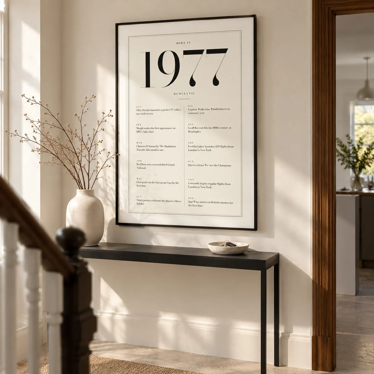 1977 Birthday Print, framed on the wall of a smart hallway in a renovated British terrace with warm white walls and a pale stone floor