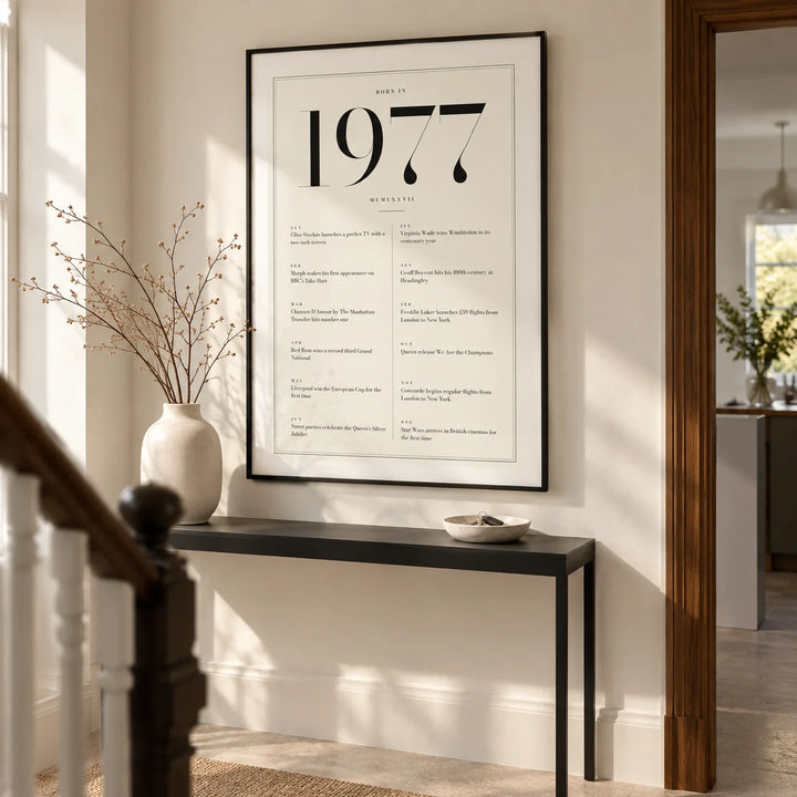1977 Birthday Print, framed on the wall of a smart hallway in a renovated British terrace with warm white walls and a pale stone floor