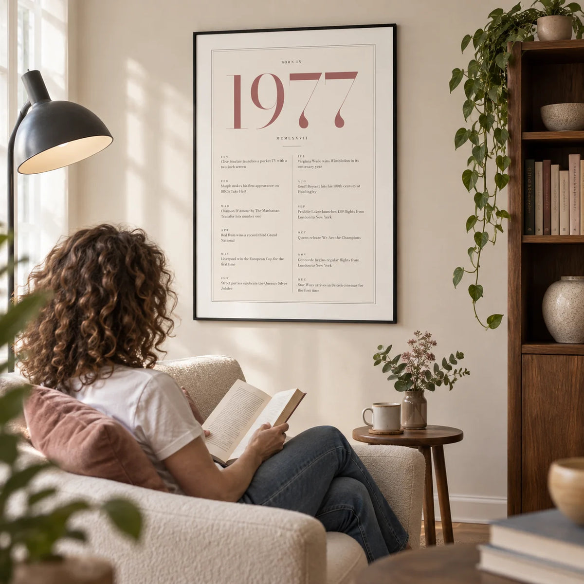 1977 Pink Birthday Print, framed on the wall of a quiet reading corner in a mature couple's UK flat with a warm white wall and a low walnut bookcase in a living room