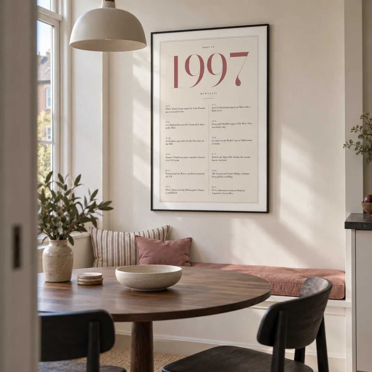 1997 Pink Birthday Print, framed on the wall of a compact modern dining nook in a UK city flat with ivory walls and a built-in bench