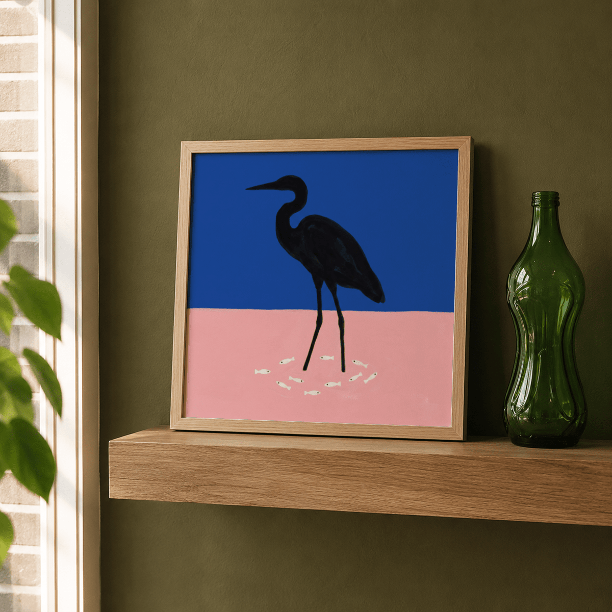 Framed bird silhouette artwork resting on wooden shelf