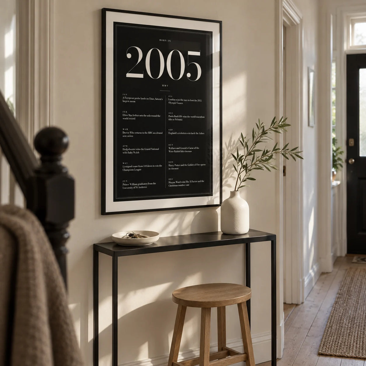 2005 Black Birthday Print, framed on the wall of a narrow hallway in a modern UK terraced home with a warm white wall and pale timber floor