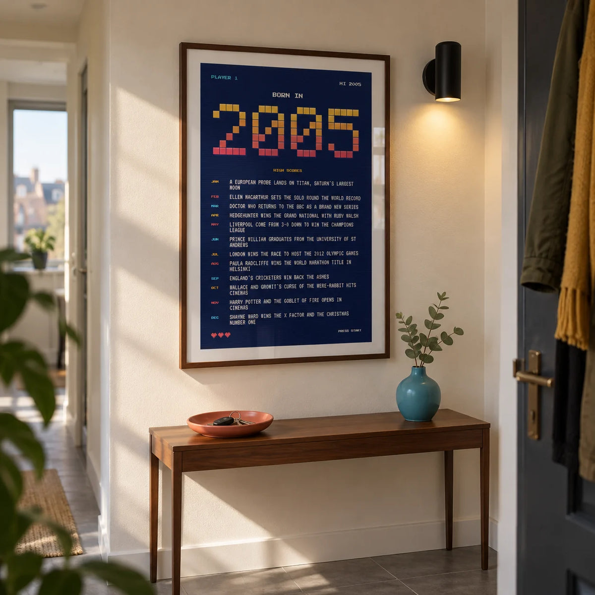 2005 Pixel Art Print, framed on the wall of a narrow entrance hallway in a young adult's UK city flat with a warm white wall and simple grey floor tiles