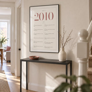 2010 Pink Birthday Print, framed on the wall of a light hallway in a modern UK terraced family home with a warm white wall and pale oak floor