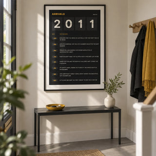 2011 Arrivals Board Print, framed on the wall of a crisp entrance hallway in a renovated UK semi-detached home with a cream wall and plain grey floor