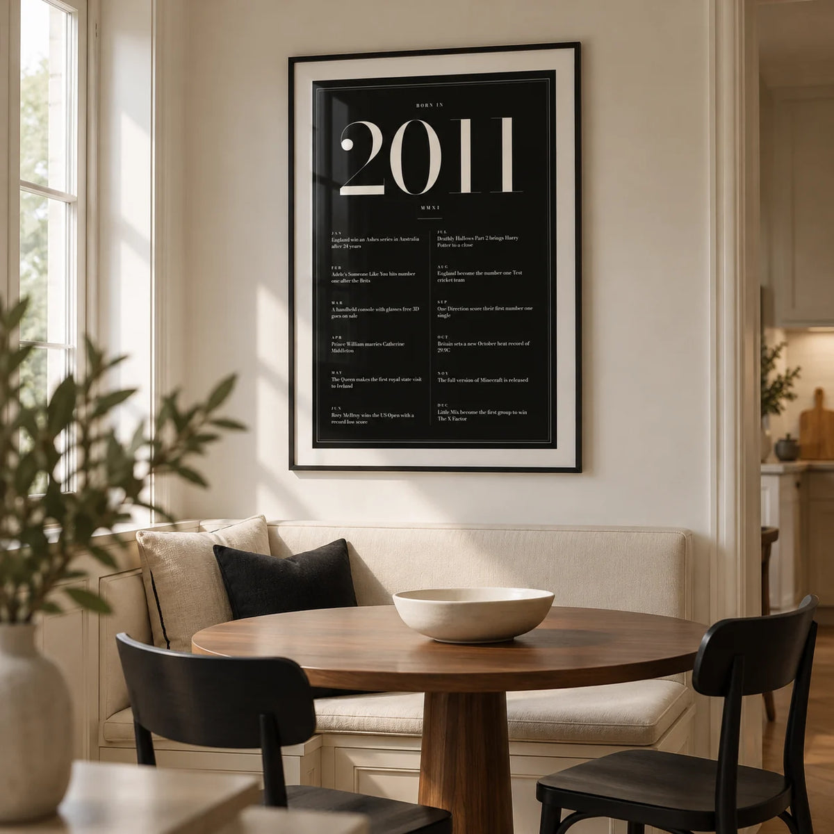 2011 Black Birthday Print, framed on the wall of a modern dining nook in a British family home with a warm white wall and a built-in cream bench